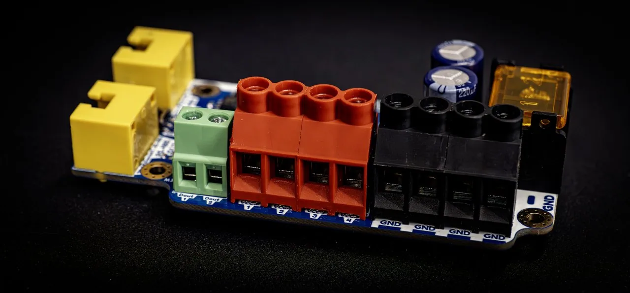 QuinLED Diff-Adv board close-up, two yellow RJ45 jacks, green/red/black multi-pin terminals, blue capacitors and an amber blade fuse