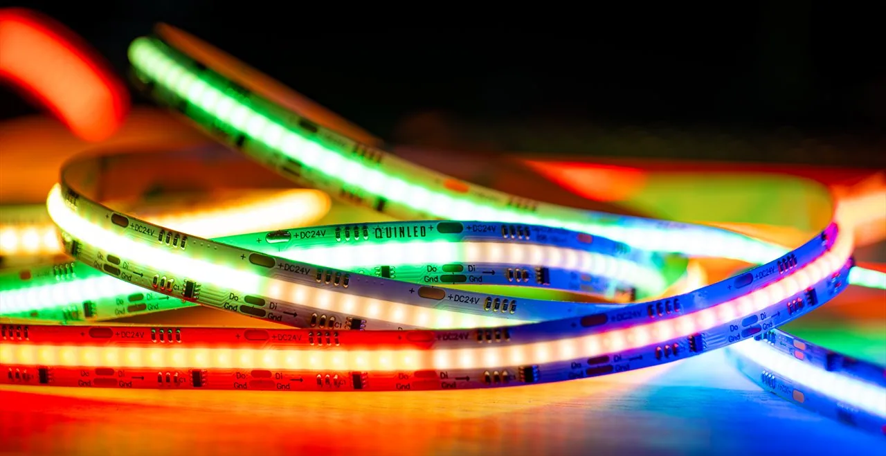 QuinLED Dig-COB-RGBW-896-160 COB strip coiled close-up, glowing red, green, blue and white zones with QUINLED and +DC24V/Do/Di/Gnd markings