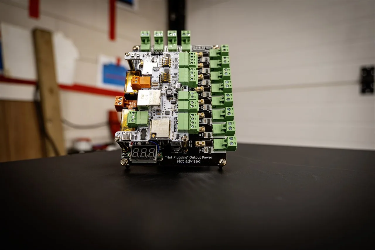 QuinLED Dig-Octa Power-5HV front-on, assembled on a Brainboard with green terminals and a voltage display in a workshop