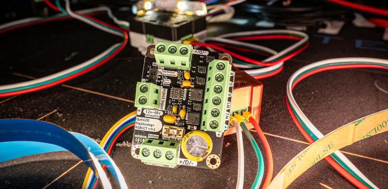 QuinLED dig2analog+ RGBCCT board wired up on a workbench among coiled LED strips and coloured test leads